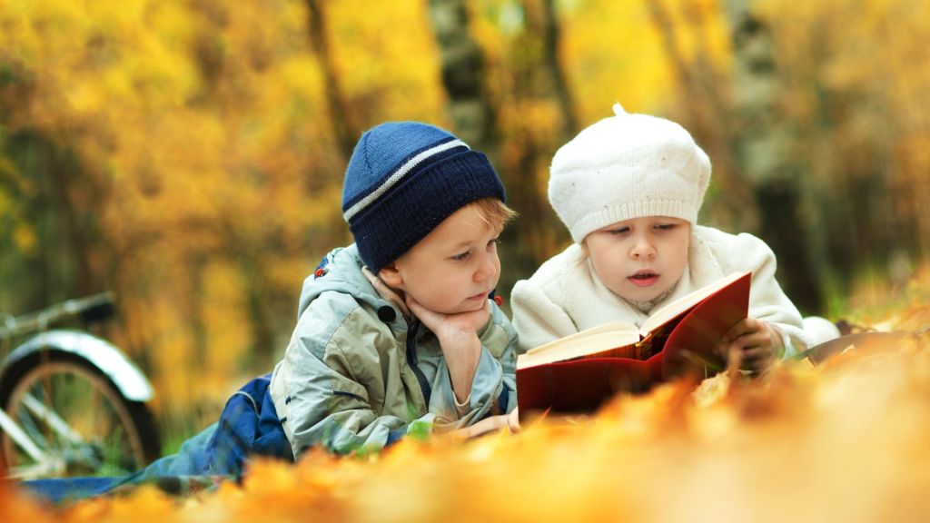 Children reading picture books during the fall season.
